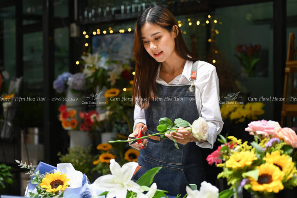Photo of female florist creating beautiful bouquet of colorful different flowers in her floral shop. Business, sale and floristry concept.