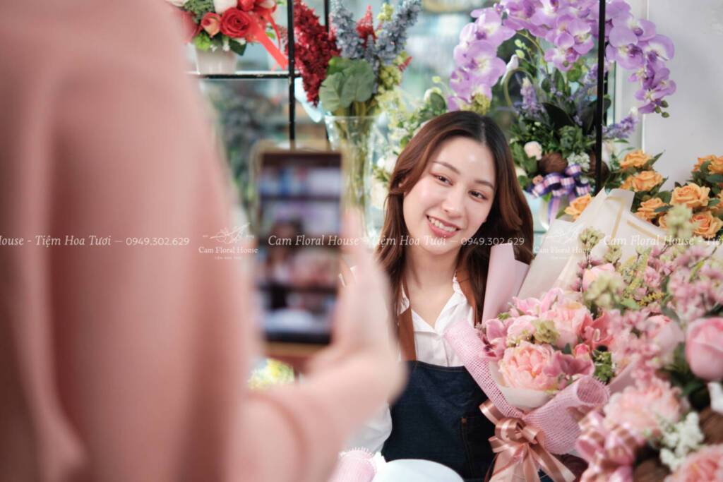 Young female florist demonstrates floral arrangements via online live