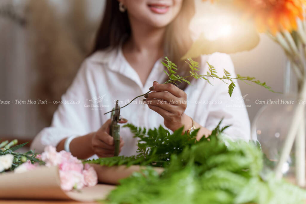 Startup, small business, flower shop. Young pretty florist putting a flower on a vase